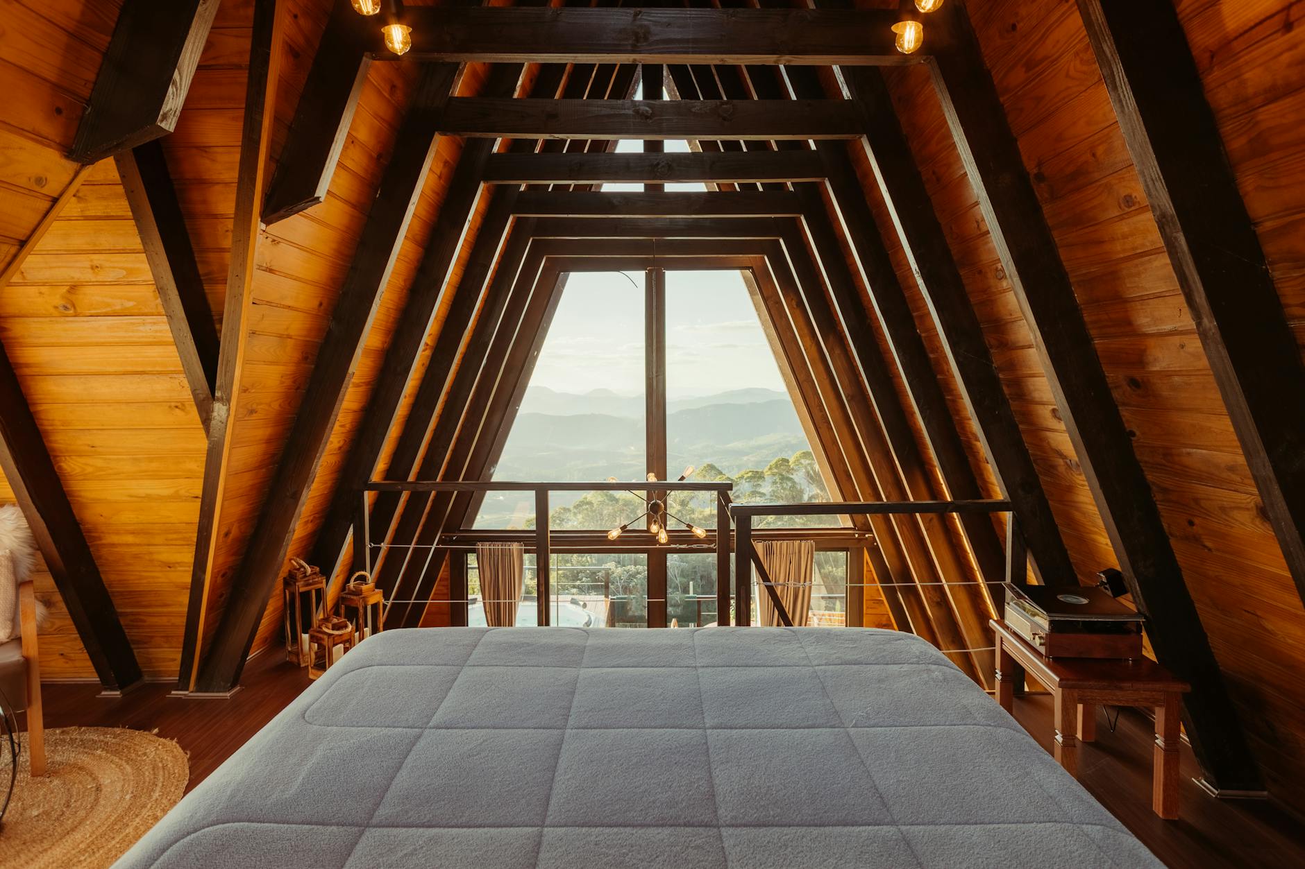 Chambre chaleureuse d’un chalet A-Frame avec grandes fenêtres donnant sur la nature